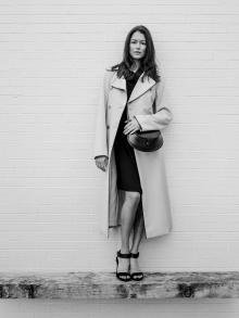 Black and white photo of female model wearing Nells Nelson trench, Jil Sander handbag and Pedro Garcia sandals