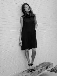 Female Model standing on bench in front of white brick wall wearing  Nemah dress and Pedro Garcia shoes.
