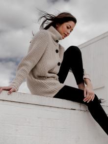 Female model sitting on ledge of building with clouds behind her wearing a full look by Iris von Arnim