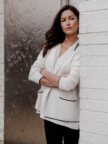 Female model with arms crossed standing by water fountain wearing Nells Nelson clothing