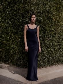 Female model standing in front of tall bamboo hedge wearing blue silk Peter Cohen and Gianvito Rossi sandal