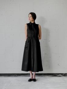 Female model standing in front of white brick wall wearing black CO clothing and black Pedro Garcia sandal