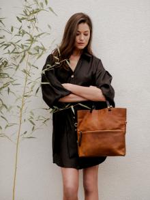 Female Model standing next to bamboo stalk wearing Veronica Beard dress with Henry Beguelin handbag