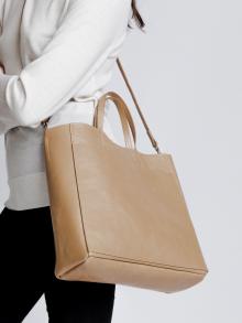 Female model in white sweater and black pants wearing bag by B May