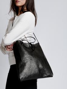 Female model in white sweater and black pants wearing bag by B May