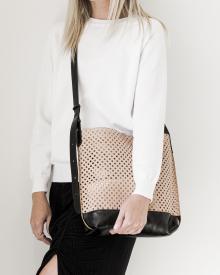 Female model against white background in white sweater and black jeans wearing threaded B. May handbag