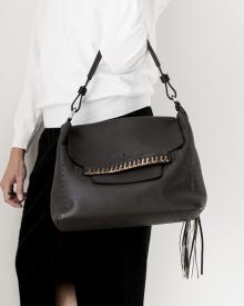 Female model against white background in white sweater and black jeans wearing black leather Henry Beguelin handbag