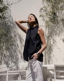 Female Model standing in front of white out door furniture and bamboo wearing Lareida Shirt QL2 Pant