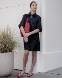 Female model against white wall looking right  wearing black Lareida Dress
