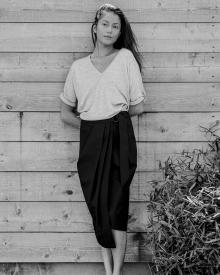 Black and white shot of female model leaning against wooden wall wearing Brunello Cucinelli