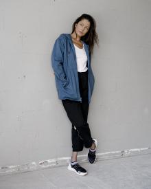 Female model leaning against white wall in dramatic lighting wearing Stella McCartney