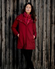 Woman standing against wooden fence wearing red Herno Waterproof Coat and black R13 Jean