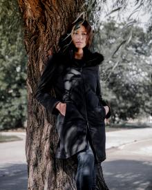 Model standing against willow tree wearing black Herno Fur Trim Coat and R13 Alison Skinny Jean