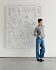 Woman standing in front of painting wearing gray Nellie Partow shirt