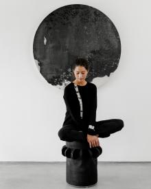 Woman model sitting on black wood stool wearing black Suzusan Crew Neck Sweater & Cardigan and Frame Skinny Pant