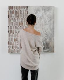 Female model wearing CO cable knit sweater in front of painting