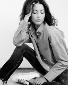 Black and white photo of model sitting on floor against white wall wearing 6397 Shirt and R13 Jean