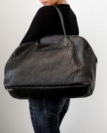 Woman wearing black sweater and blue jeans holding black Amiacalva Tote