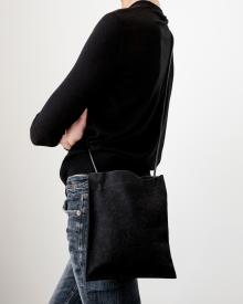 Woman wearing black sweater and blue jeans holding black Amiacalva Pouchette crossbody