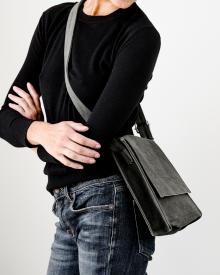 Woman wearing black sweater and blue jeans holding gray Amiacalva Crossbody