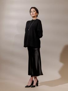 Model wearing black sweater and black satin skirt
