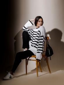 Model wearing a striped sweater sitting in a chair