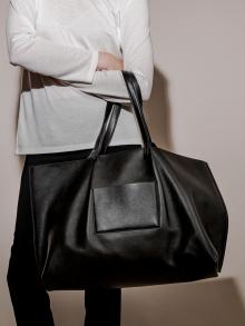 Model carrying black larger leather bag
