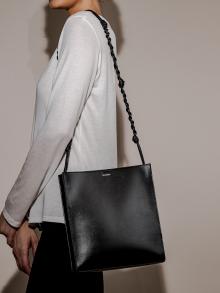 Model wearing a long strapped black leather purse