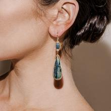 Model wearing gold, blue textured dangle earring