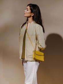 Model wearing cream jacket and yellow purse